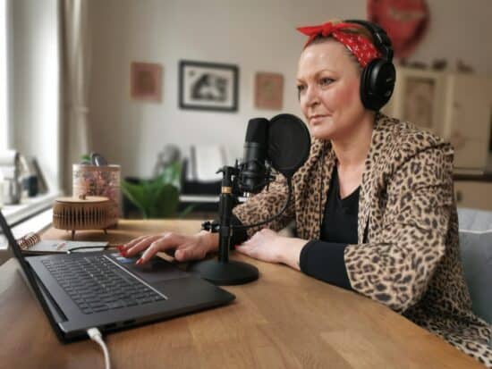 Martina Leisten mit Podcast-Mikro vor dem Laptop